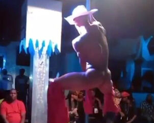 Beefy masculine stripper clad like cowboy dancing at night